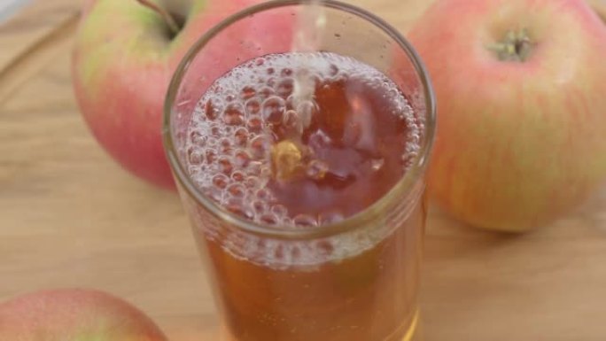 苹果汁被倒入玻璃杯中。健康的食物和饮料。选择性聚焦