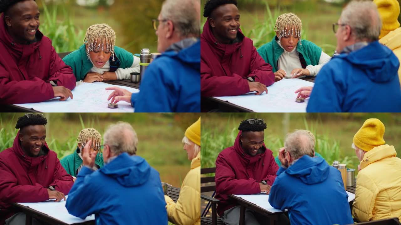 老年夫妇和非洲族裔青少年在公园的桌子上看着地图，喝茶。计划一起旅行。