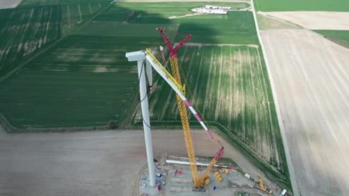 在施工过程中产生电力的风车，起重机提升风车的叶片。