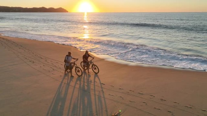 沿着海滩推自行车的夫妇的鸟瞰图