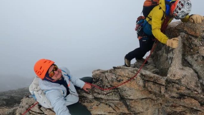 一队登山者沿着欧洲阿尔卑斯山的陡峭山峰移动。对着镜头微笑
