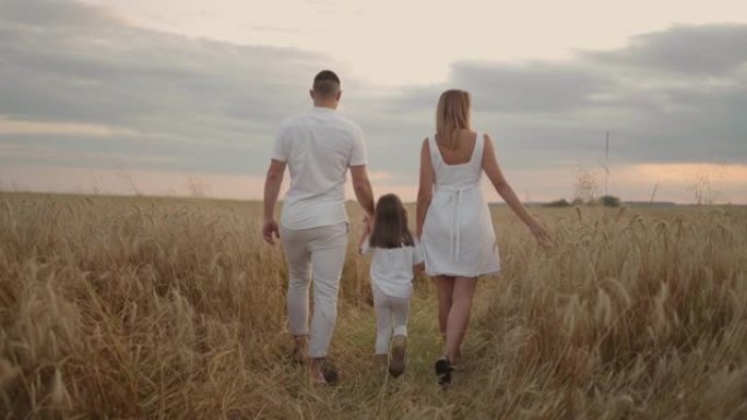 慢动作: 幸福的农民家庭带着孩子，正在麦田上行走。健康的母亲，父亲和小女儿一起在户外享受大自然。