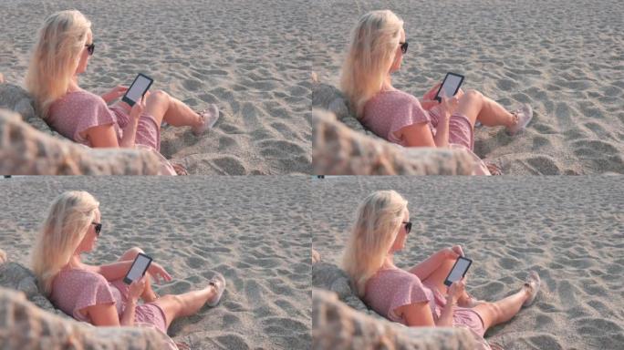 女人在海滩上放松时使用电子阅读器