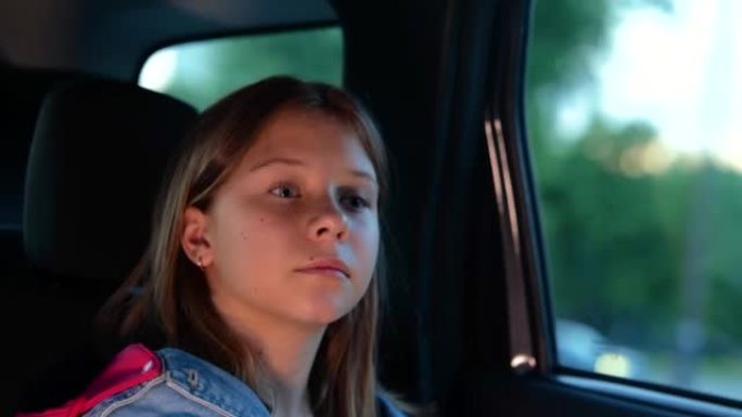 特写着严肃表情的小漂亮女孩在车里旅行，透过窗户看。悲伤的高加索女性儿童在乘车时。汽车旅行的概念