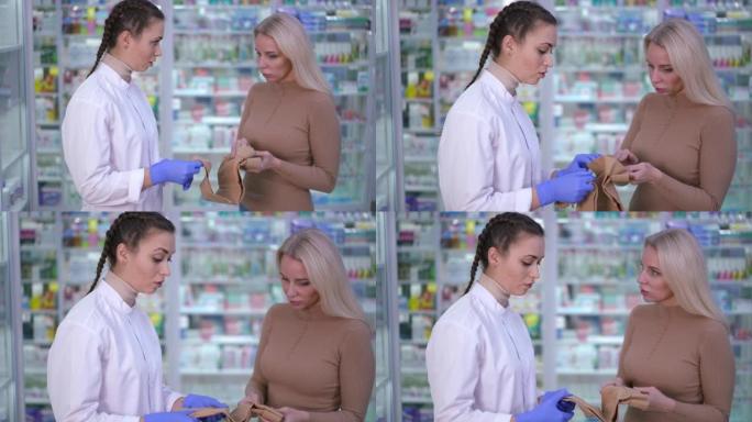 专业的年轻女子在药房与客户交谈，为医疗压缩紧身衣做广告。高加索卖方和买方讨论产品对静脉曲张的有效性。