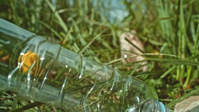 SLO MO塑料瓶与其他瓶子一起降落在草地上