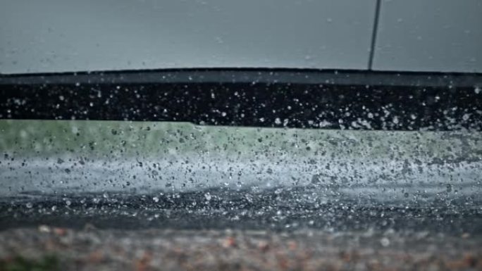 SLO MO LD汽车在雨中经过，轮胎将水溅到空中