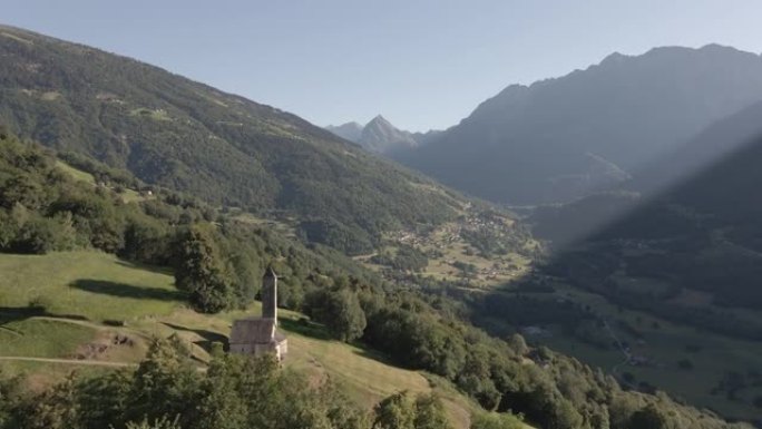 无人机拍摄到一座教堂坐落在郁郁葱葱的山坡上，后面是群山
