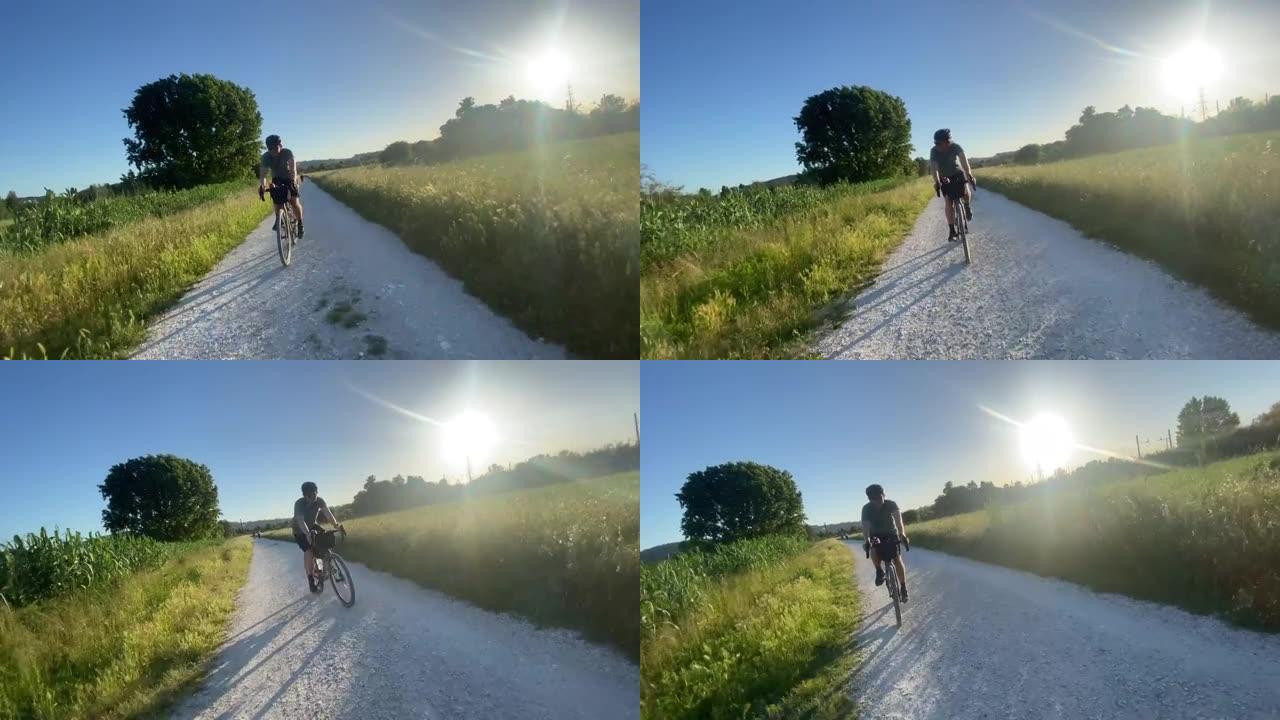 男子在日落时分在宁静的砾石小径上骑自行车，满载袋子的自行车