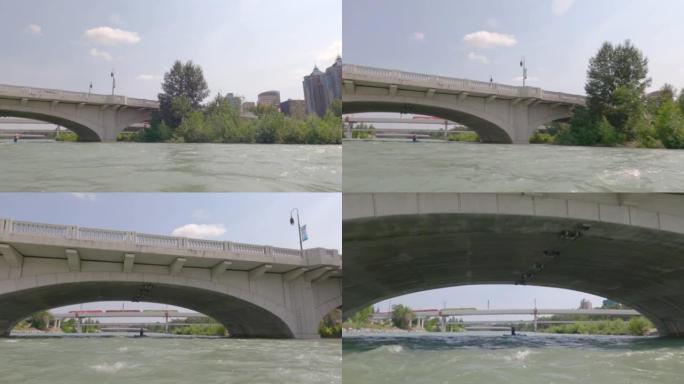 站立桨板 (SUP) 的第一人称视角，漂浮在城市河上