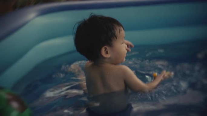 蹒跚学步的男孩和他的父亲在游泳池里享受水中的乐趣。