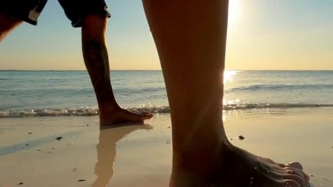 恋爱中的情侣在日落海滩散步。紫色和橙色天空的深色轮廓。腿部特写