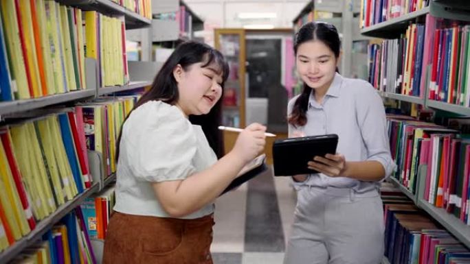 在亚洲的大学图书馆，亚洲女性正在通过图书馆的平板电脑搜索互联网。