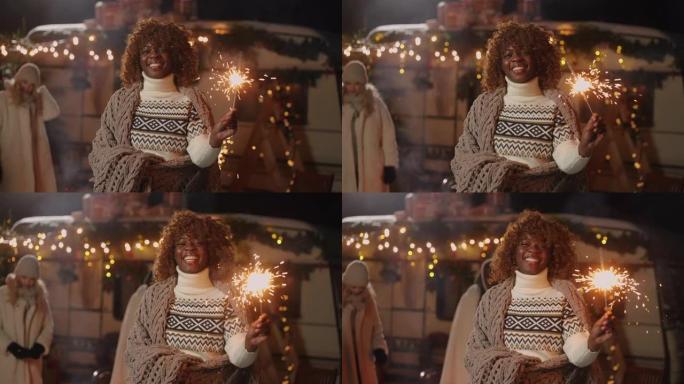 新年圣诞节市场上，手持烟火的快乐非裔美国妇女对相机微笑