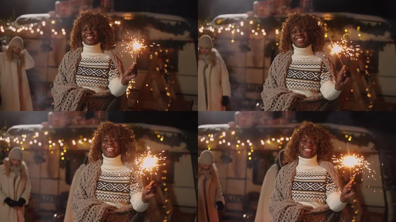 新年圣诞节市场上，手持烟火的快乐非裔美国妇女对相机微笑
