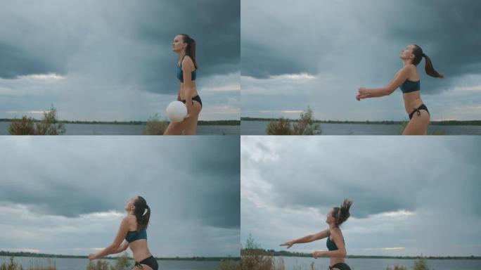 穿着比基尼的年轻女运动员正在打沙滩排球，在风景如画的阴云密布的天空中射击