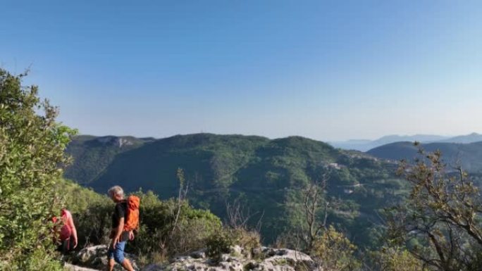 徒步旅行的夫妇沿着绿色山丘的山顶到达