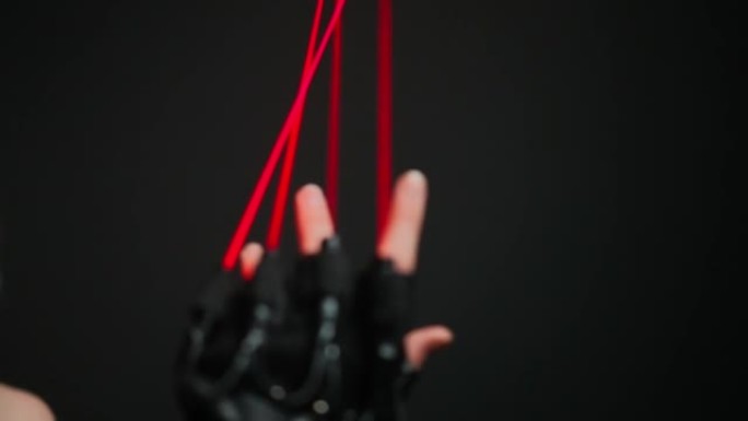 女性高加索人手上带有红色霓虹灯的特写手套，模糊的女人在黑色背景下移动手掌。穿着网络服装的女舞者在舞台