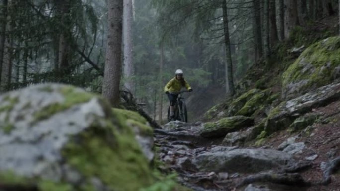 女性山地自行车手在阴雨天在森林中骑行