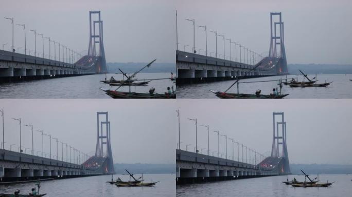 以苏拉马杜大桥为背景的爪哇海中通过的渔船。连接爪哇岛和马都拉岛的印度尼西亚最长的桥梁
