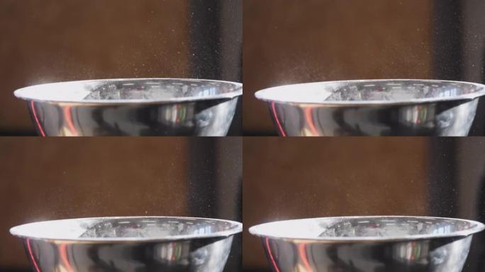从金属碗中升起的粉笔灰尘的细节拍摄