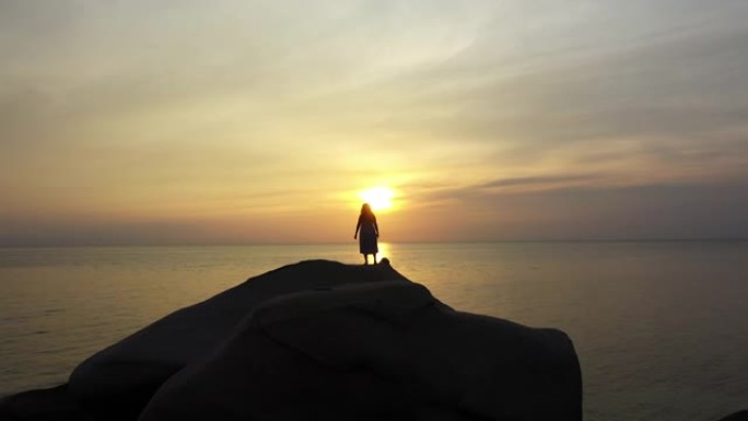 多莉在海滩日落时间拍摄站在石头上的女人