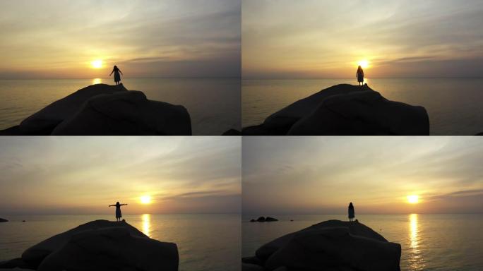 多莉在海滩日落时间拍摄站在石头上的女人