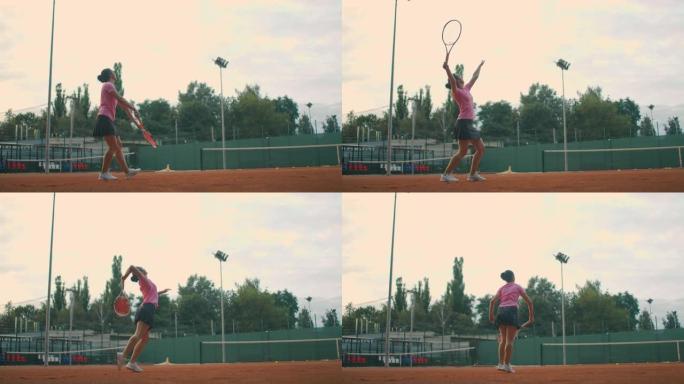 慢动作: 年轻的高加索青少年女网球运动员在比赛或练习中服役。网球运动员在红土场上服役。
