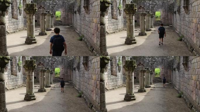 男孩走过废墟喷泉修道院石柱的后视图