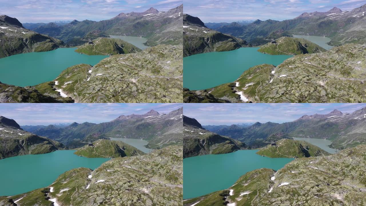 从上面看雄伟的阿尔卑斯山。陡峭的山坡被雪覆盖，瀑布从湖上掉下来