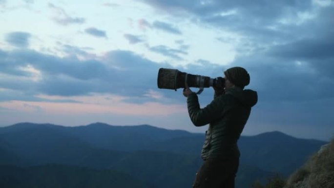 男摄影师拿着大变焦镜头，看着风景，拍照