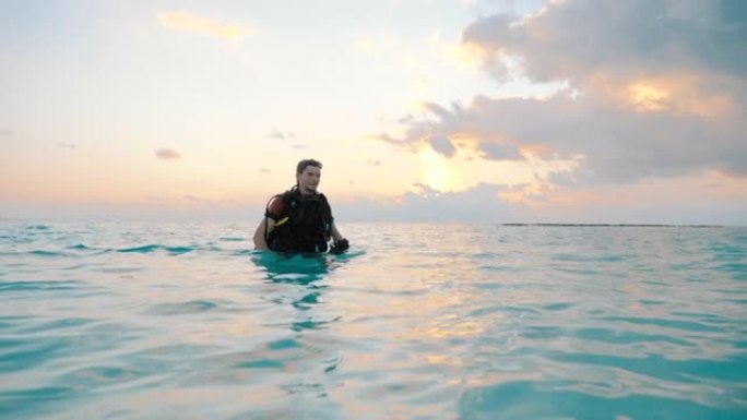 潜水员在日落时走出大海来到海滩