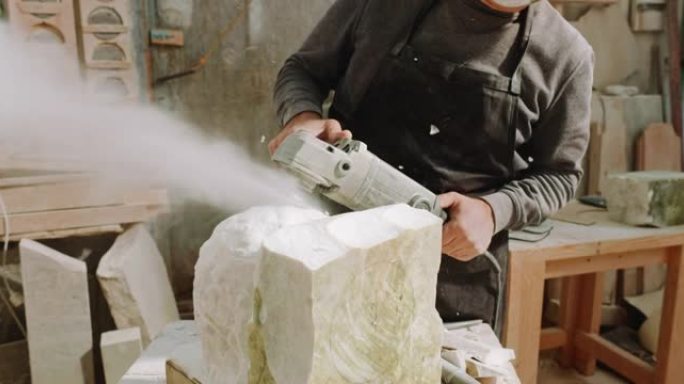 SLO MO男雕塑家使用角磨机使雕塑表面均匀