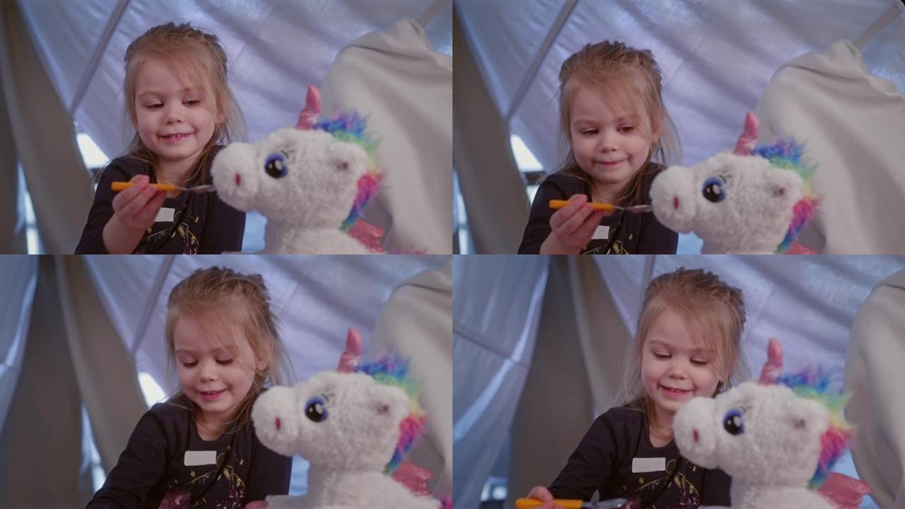 可爱的小女孩在舒适的天篷床上玩她的独角兽玩具。假装喂它