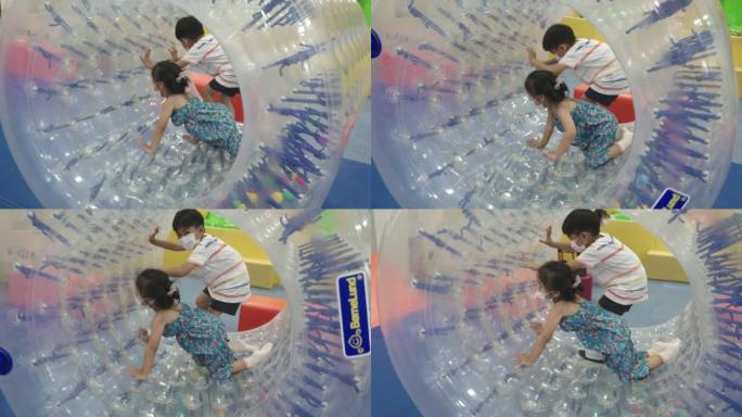 快乐的亚洲儿童在娱乐中心充气城堡玩得开心，巨大的充气滚轮