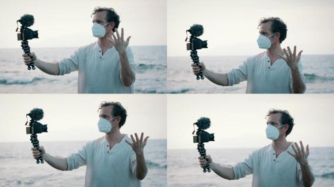 戴着口罩的男子在海洋附近与手持摄像机交谈