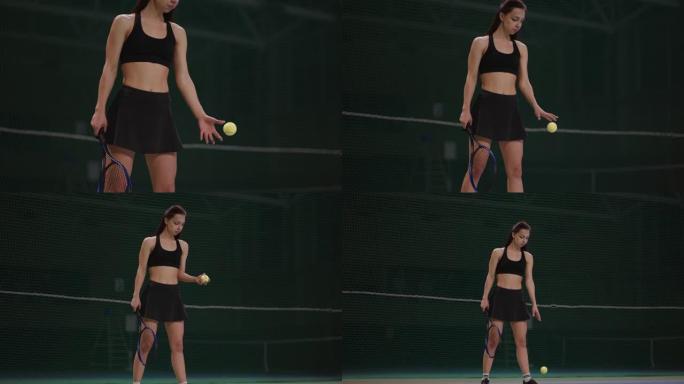 运动女子在发球前将球扔在网球场上，在室内进行肖像射击，运动和积极的生活方式