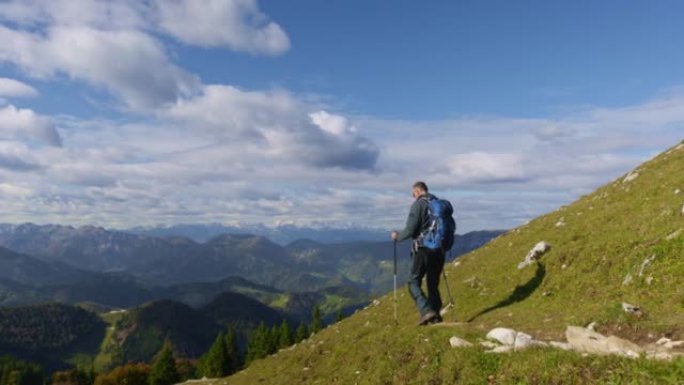 高级男性徒步旅行者在阳光下的风景优美的小径上下山