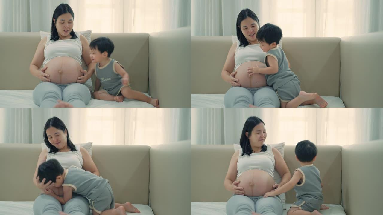 小男孩和怀孕的妈妈肚子玩耍和接吻