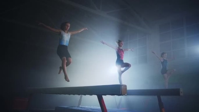在儿童体育学校进行艺术体操训练时，三名少女运动员正在平衡木上行走