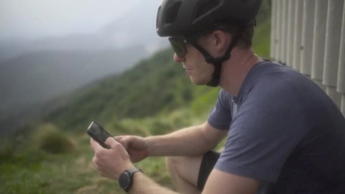 骑自行车的人在山上使用电话在棚子附近停下来