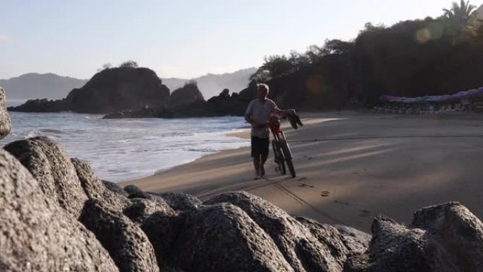 男子在空旷的海滩上推自行车，望向大海