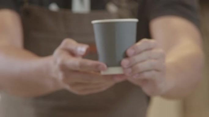 亚洲男子咖啡师在咖啡店里为顾客提供热咖啡杯