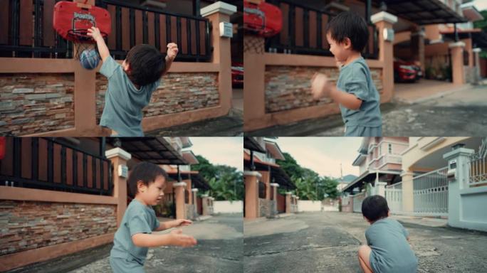 亚洲蹒跚学步的男孩在家门口打篮球