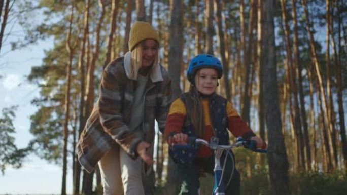 一位母亲教女儿骑自行车。一个戴着头盔的女孩学会和母亲一起骑自行车散步