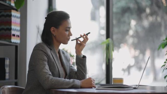 年轻的西班牙裔，阿拉伯妇女手持设备收听音频语音邮件离开响应使用智能手机小工具上的扬声器，共享消息使用