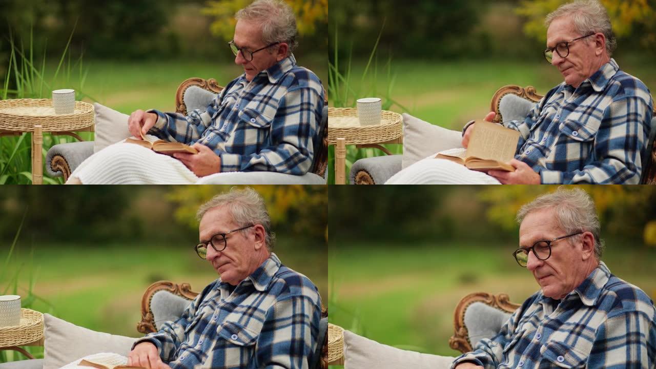 生病的老年男性患者在外面的椅子上看书
