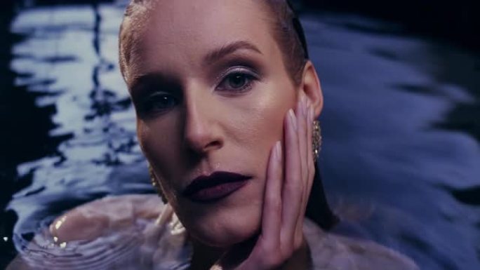 浮动放松。诱人的女人从黑暗的水中冒出来。抚摸她的长发和柔软的皮肤。奢华美容护理
