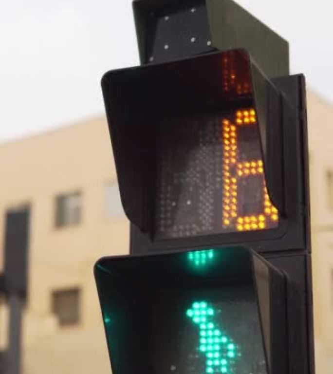 行人交通信号灯标志的垂直特写视图。绿灯，倒计时时间变为红色停车灯。是时候安全过马路了