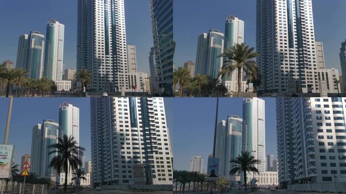 阿拉伯联合酋长国沙迦-2022年4月3日: 背景上的现代摩天大楼、塔楼和椰枣树。沙迦阿联酋城市路